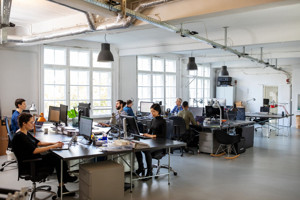 Travailleurs habillés de façon décontractée dans un bureau à aire ouverte très fréquenté. Gens d'affaires travaillant dans un bureau moderne.
